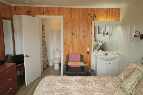 a bedroom with a bed and a sink and a bathroom at Auberge St-Tite-des-Caps in Saint-Tite-des-Caps