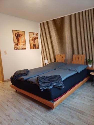 a large bed in a bedroom with two chairs at Gutheils-Ferienwohnung in Nanzdietschweiler