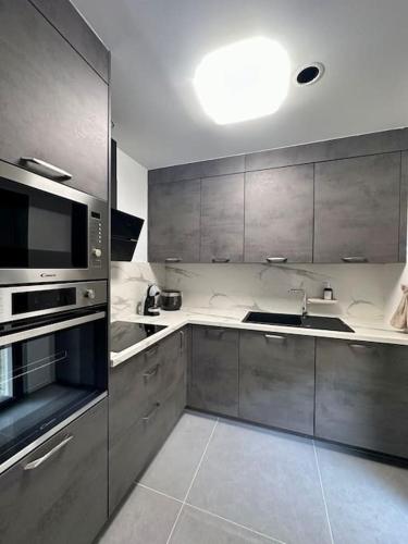 une cuisine avec des armoires en acier inoxydable et un évier dans l'établissement Maison familiale moderne aux portes de Paris, à Vitry-sur-Seine