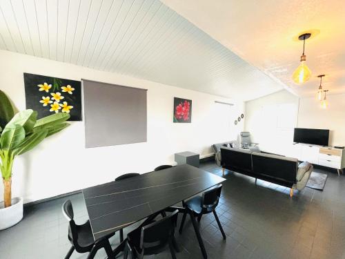 a dining room with a black table and chairs at Penthouse Happiness in Papeete