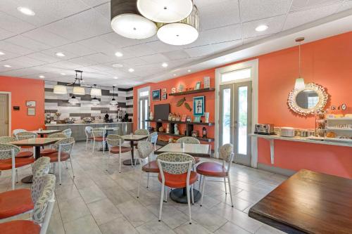 a restaurant with orange walls and tables and chairs at Best Western Plus St. Simons in Saint Simons Island