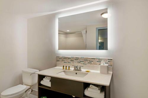 a bathroom with a sink and a toilet and a mirror at Best Western Plus St. Simons in Saint Simons Island