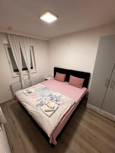 a bedroom with a large bed with pink and white sheets at Guest House deluxe in Orašje