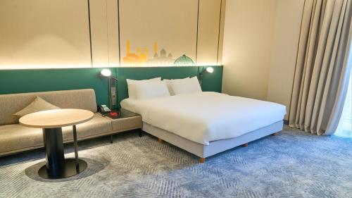 a bedroom with a bed and a couch and a table at Holiday Inn Tashkent City by IHG in Tashkent