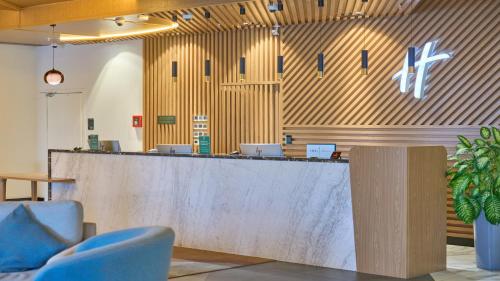 a lobby with a reception counter with blue chairs at Holiday Inn Tashkent City by IHG in Tashkent