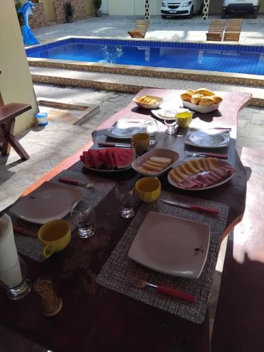 einen Tisch mit Teller mit Speisen neben einem Pool in der Unterkunft Pousada Alto do Tambá in São Francisco