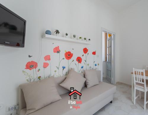 a living room with a white couch with flowers on the wall at Casa Bianca bnb,Big Terrace,10 min Airport Beaches in Bitonto