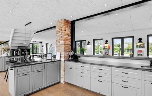 a kitchen with white cabinets and a brick wall at Gubbegård in Neksø