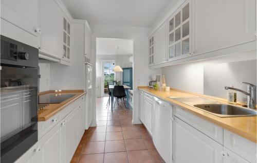 a white kitchen with white cabinets and a sink at Three-Bedroom Holiday Home In Blavand in Blåvand