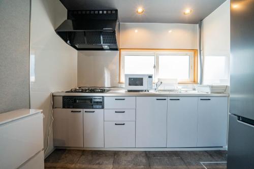 a kitchen with white cabinets and a sink and a window at The Jardin in Kami-furano