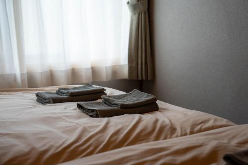 three towels are stacked on top of a bed at The Jardin in Kami-furano