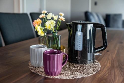 a coffee pot and cups on a table with flowers at The Jardin in Kami-furano