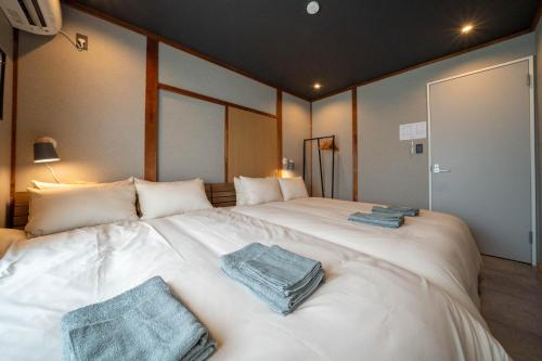 a large white bed with two towels on it at The Jardin in Kami-furano