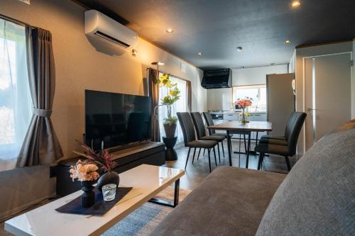 a living room with a couch and a tv and a table at The Jardin in Kami-furano