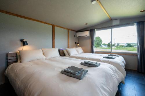 two beds in a room with towels on them at The Jardin in Kami-furano