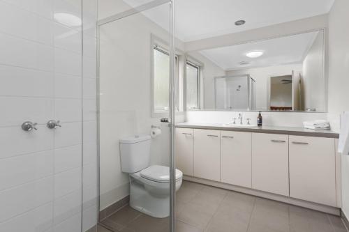 ein weißes Bad mit einem WC und einer Glasdusche in der Unterkunft Number 6 at The Bay in Apollo Bay