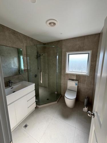 a bathroom with a shower and a toilet and a sink at Dream House 3 in Auckland