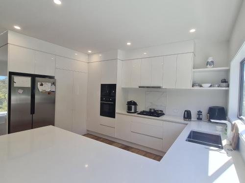 a kitchen with white cabinets and a stainless steel refrigerator at Dream House 3 in Auckland