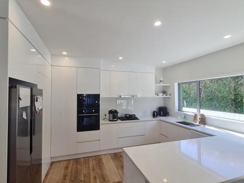 a kitchen with white cabinets and a black refrigerator at Dream House 3 in Auckland