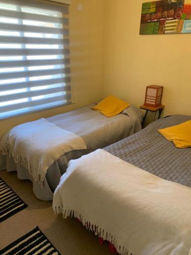 three beds in a room with a window at Casa de la Ribera Rengo in Valdivia