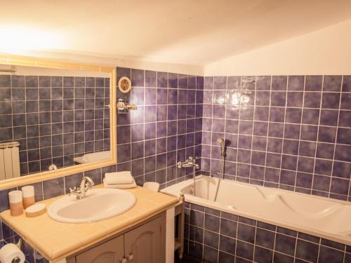 W wyłożonej niebieskimi kafelkami łazience znajduje się umywalka i wanna. w obiekcie Villa Martinet w mieście Carpentras