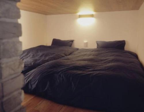 ein Bett in einem Schlafzimmer mit einer schwarzen Bettdecke in der Unterkunft Shikochu Base - Vacation STAY 76591v in Shikokuchuo