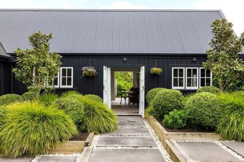 a black house with a black roof at Hawthorn Cottage - Deluxe Private Guesthouse in Tamahere
