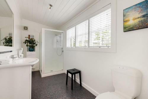 a white bathroom with a toilet and a sink at Hawthorn Cottage - Deluxe Private Guesthouse in Tamahere