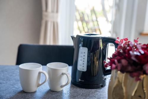 two white coffee cups sitting next to a coffee maker at The Chateau in Yoichi