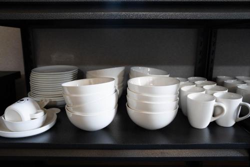 a group of white cups and plates on a shelf at The Chateau in Yoichi