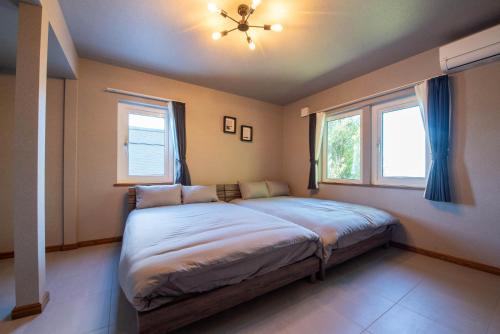 a bedroom with a large bed with two windows at The Chateau in Yoichi