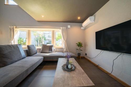 a living room with a couch and a large flat screen tv at The Chateau in Yoichi