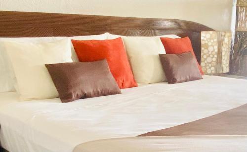 a bed with colorful pillows on top of it at Excellence Suites Orient Beach Oceanview King-Size Beach Pool Parking in Cul de Sac