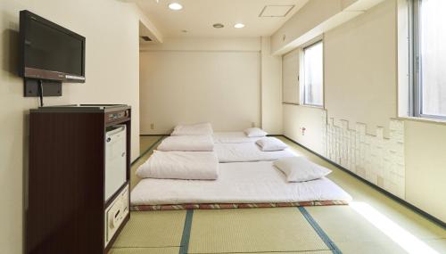 a room with three beds and a flat screen tv at Hotel Paco Obihiro Chuo in Obihiro