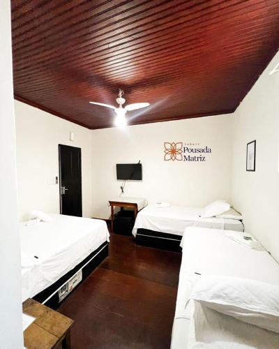 a room with two beds and a wooden ceiling at Pousada Matriz in Paraty