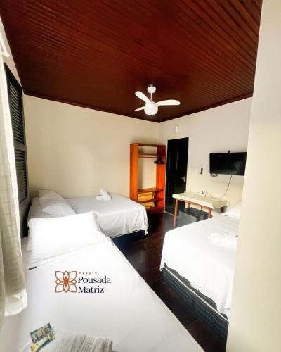 a hotel room with three beds and a ceiling at Pousada Matriz in Paraty