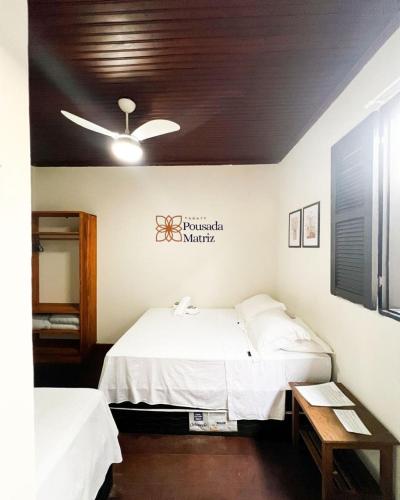 a bedroom with two beds and a ceiling fan at Pousada Matriz in Paraty