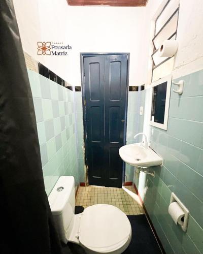 a bathroom with a toilet and a sink and a black door at Pousada Matriz in Paraty