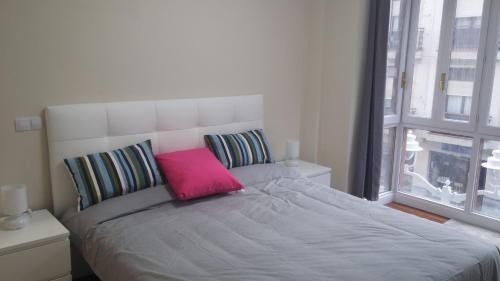 a bedroom with a large bed with a pink pillow at Apartamento Villarias in Bilbao