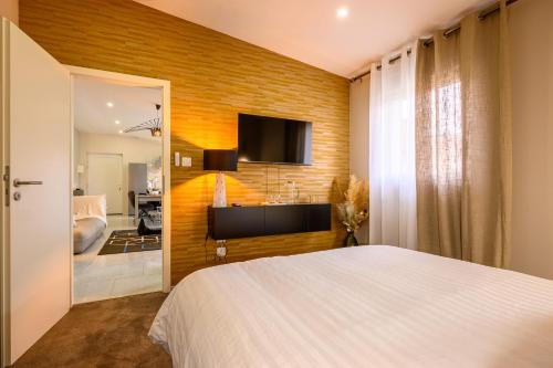 una camera con letto e TV su un muro di mattoni di Le Charles 1 a Montbéliard