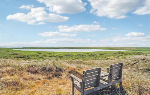 a bench sitting on top of a field with a lake at Holiday Home Sdr Klitvej Hvide Sande Denm in Havrvig