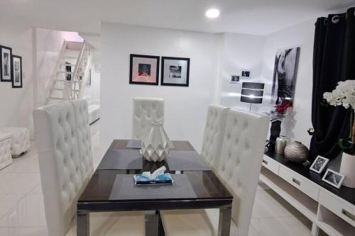 a dining room with a table and white chairs at Kandi Paramount Executive 1BR 140sqm and 400mbps in Angeles