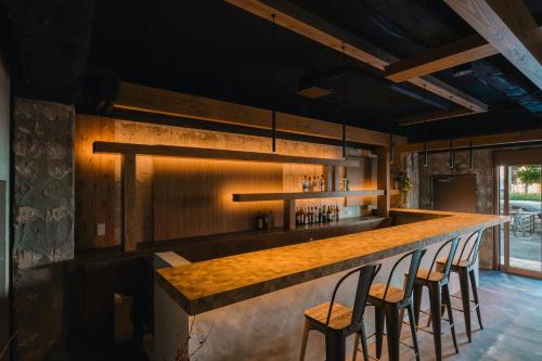 a bar with four chairs at a counter with lights at 3U NAMBA MINAMI - Doyanen Hotels in Osaka