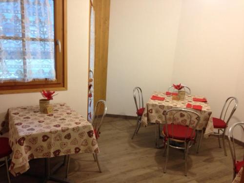 een kamer met twee tafels en stoelen met rode zittingen bij B&B Rendena Chalet in Strembo