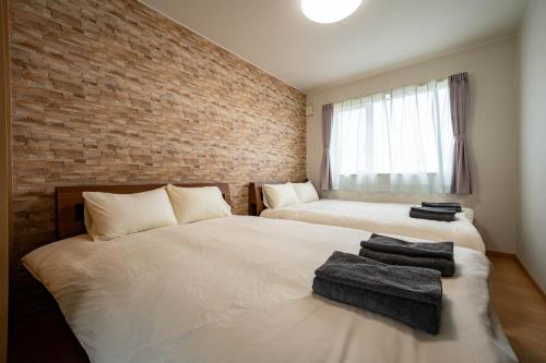 a bedroom with two beds and a brick wall at lapis lazuli in Kami-furano