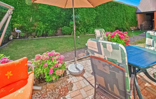 a patio with a table and an umbrella and flowers at Ferienhaus Wesenberg in Wesenberg
