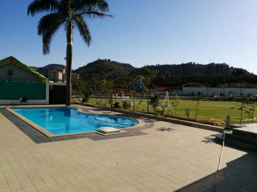 a swimming pool with a palm tree in a yard at Hotel Lake View in Saputara