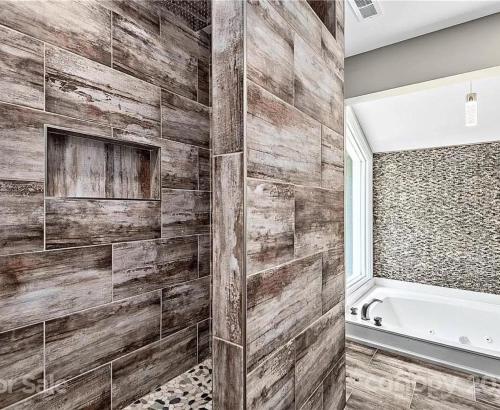 a bathroom with a wooden wall with a tub at Secluded oasis in Asheville! GAME room MOVIE theater HOT tub - 20 min to Biltmore! in Fairview