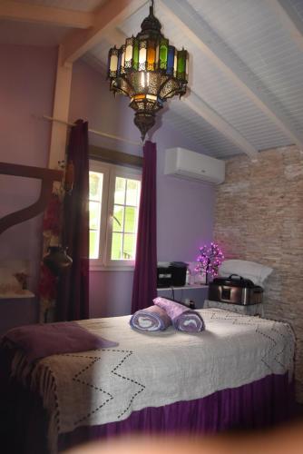 a bedroom with a bed with purple sheets and a chandelier at Gite d'Arles Bungalow "L'Oasis" in Le Moule