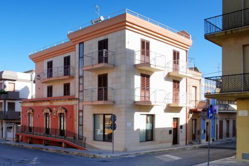 a white building with balconies on a street at B&B Sikelia in Ispica